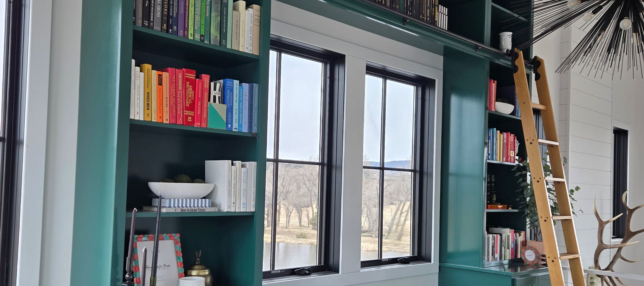 custom built-in bookshelf with sliding ladder and window seat in a Colorado home