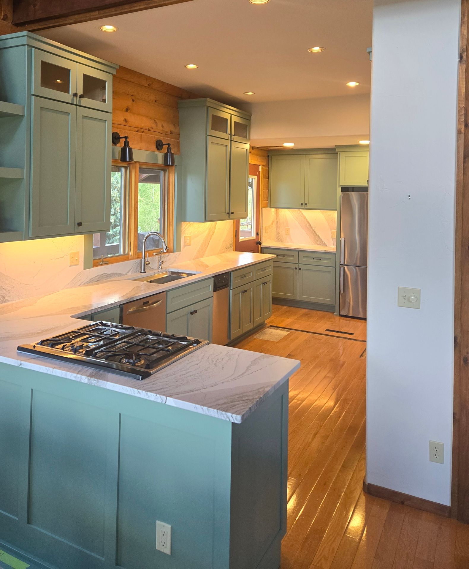 green builtin bookshelves around a window with a sliding ladder